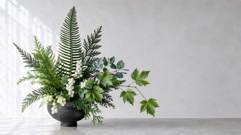 Pacific Northwest woodland foliage for designers. A sculptural woodland arrangement in a dark pedestal vase featuring Western sword fern fronds, cedar tips, eucalyptus, grapevine foliage, and clusters of white snowberry berries.